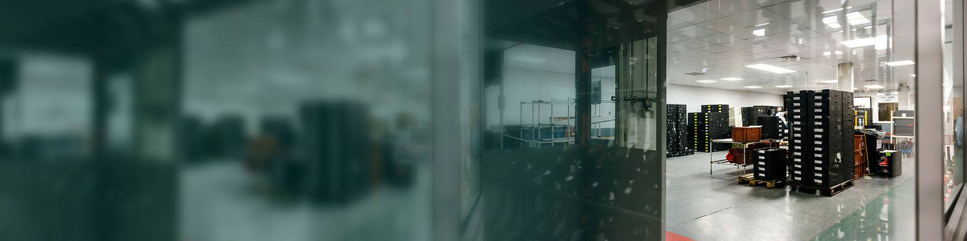 Lots of black boxes stacked on top of each other in a warehouse.