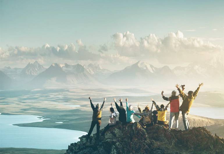 Happy team on top of a mountain cheering and celebrating their success together
