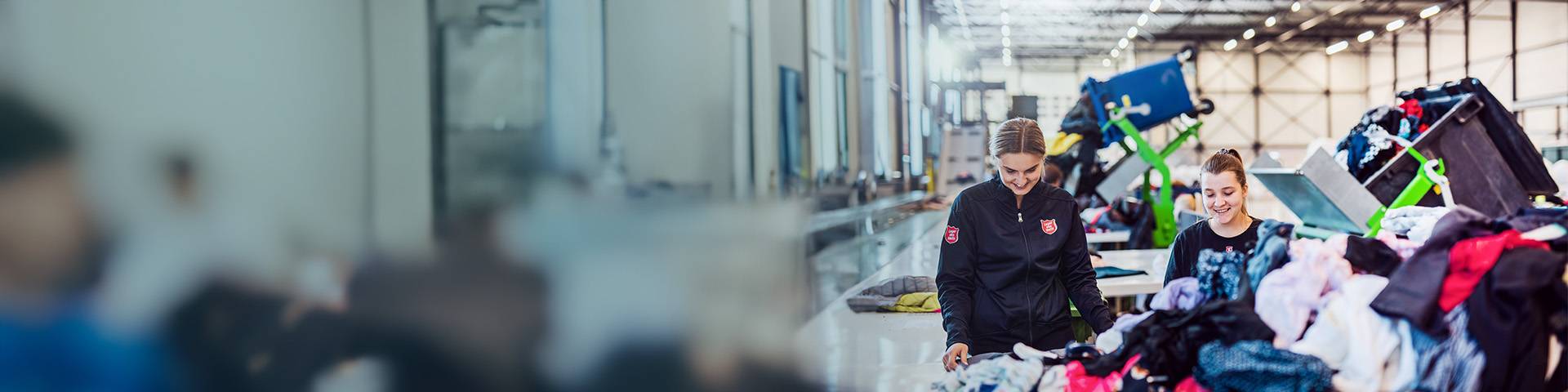 Two employees sort clothes in a factory.