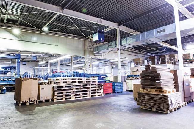 Large industrial hall with stacked pallets and cardboard packaging.