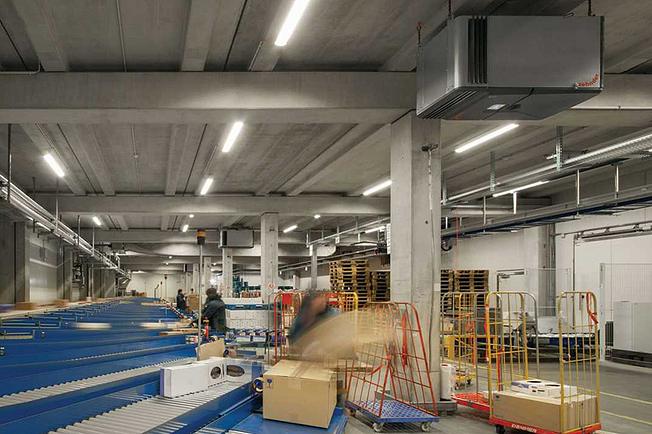 Mitarbeiter sortieren Pakete, welche über ein Förderband verteilt werden.