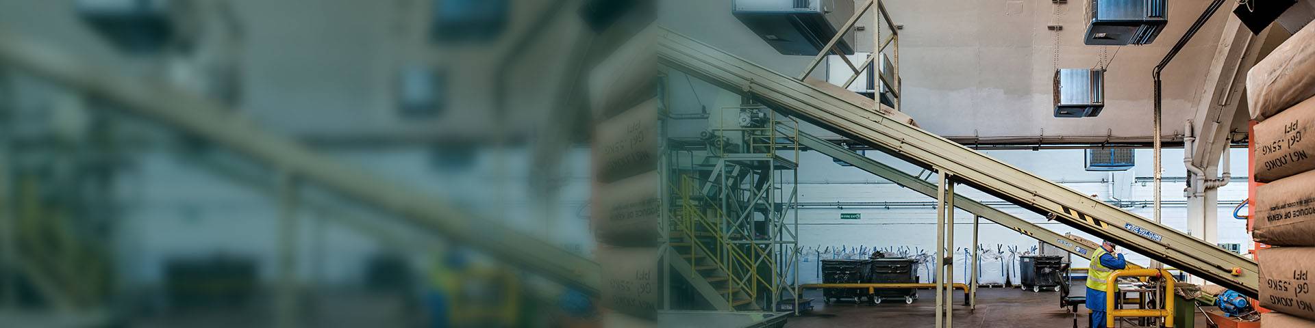 Industrial air cleaner above a conveyor belt in an industrial hall.