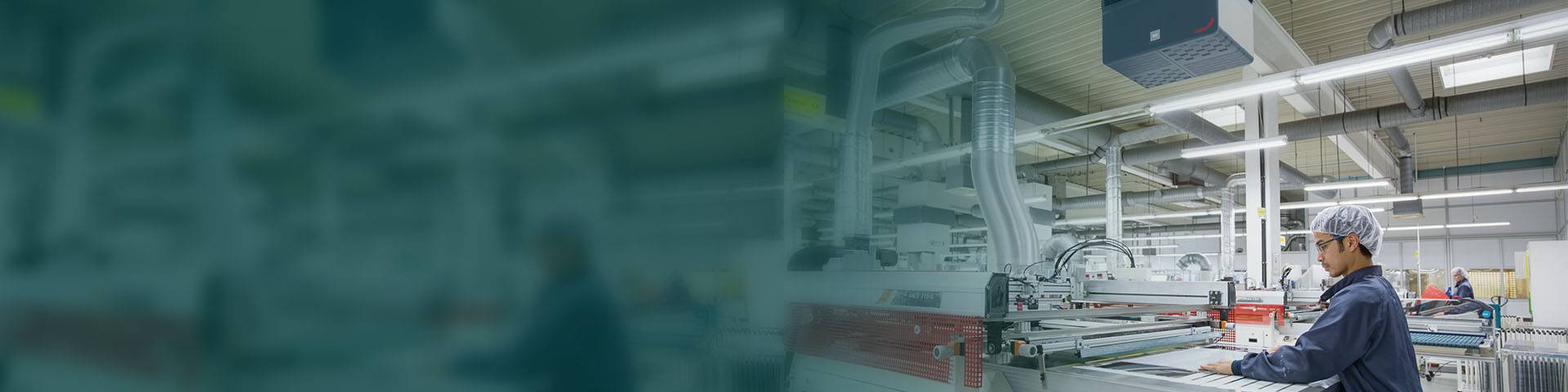 Employees working on a production line in a modern production hall with an industrial air filter system.