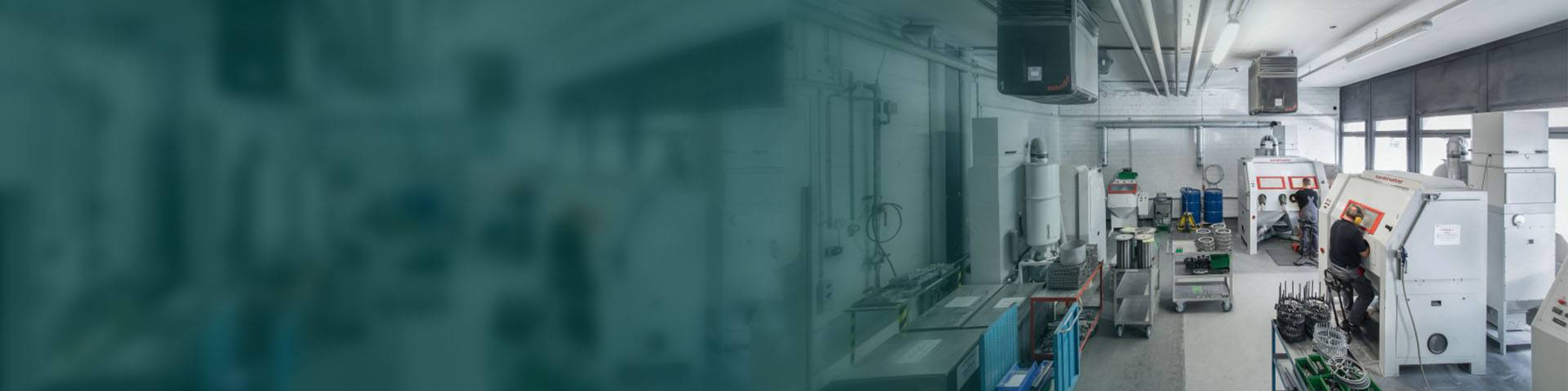 Employees working on machines in an industrial hall.