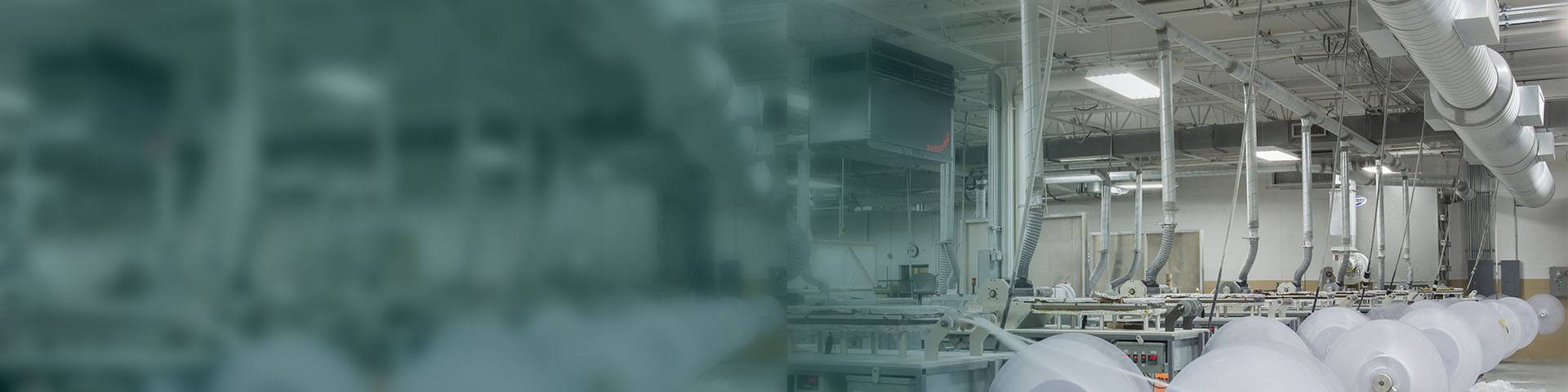 Industrial air purifier in a production hall for plastic material with large rolls.