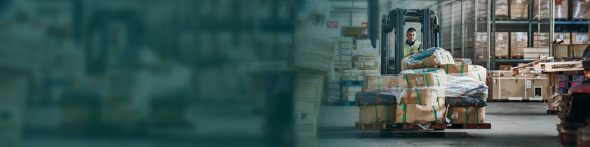 An employee in logistics drives through the hall with a forklift truck.