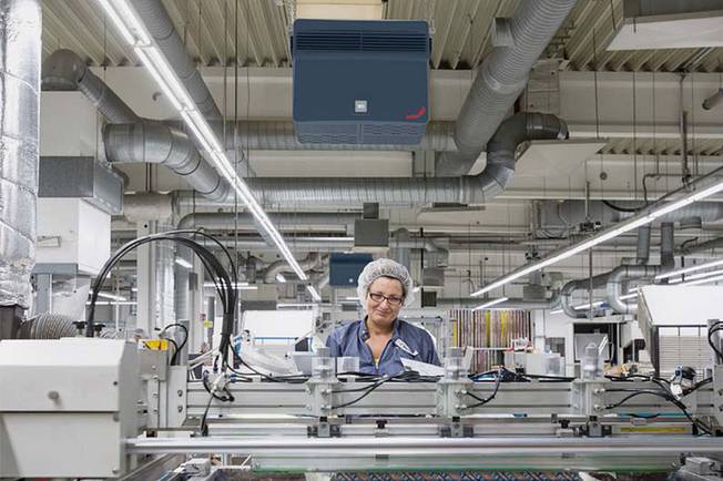 Employee working on a production line in a production hall with an industrial air filter system.