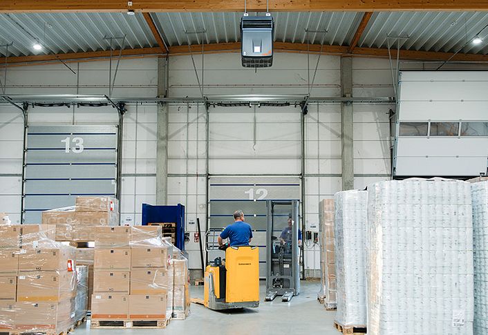 Luftreiniger in einer Halle, in der Kartons gestapelt sind.