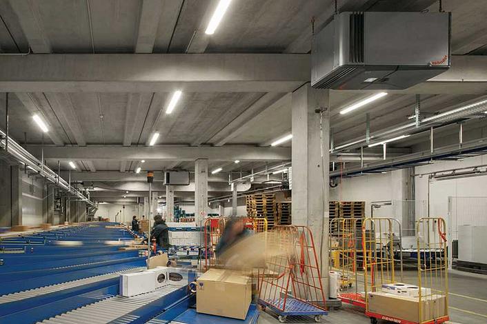 Mitarbeiter sortieren Pakete, welche über ein Förderband verteilt werden.