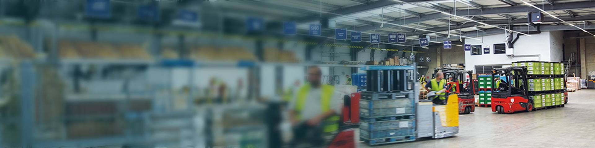 An employee in a high-visibility waistcoat stands in front of a lorry labelled DB Schenker.