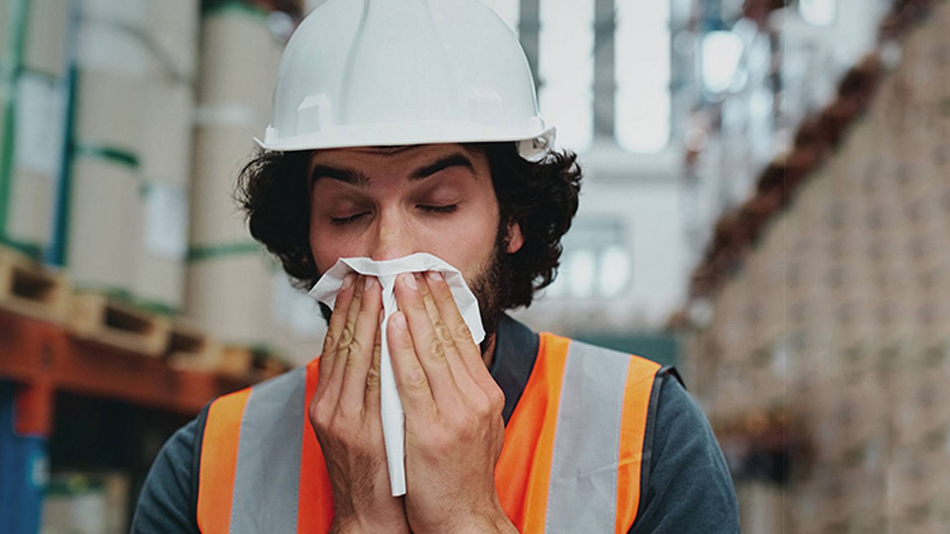 A warehouse employee blows his nose due to high dust exposure.