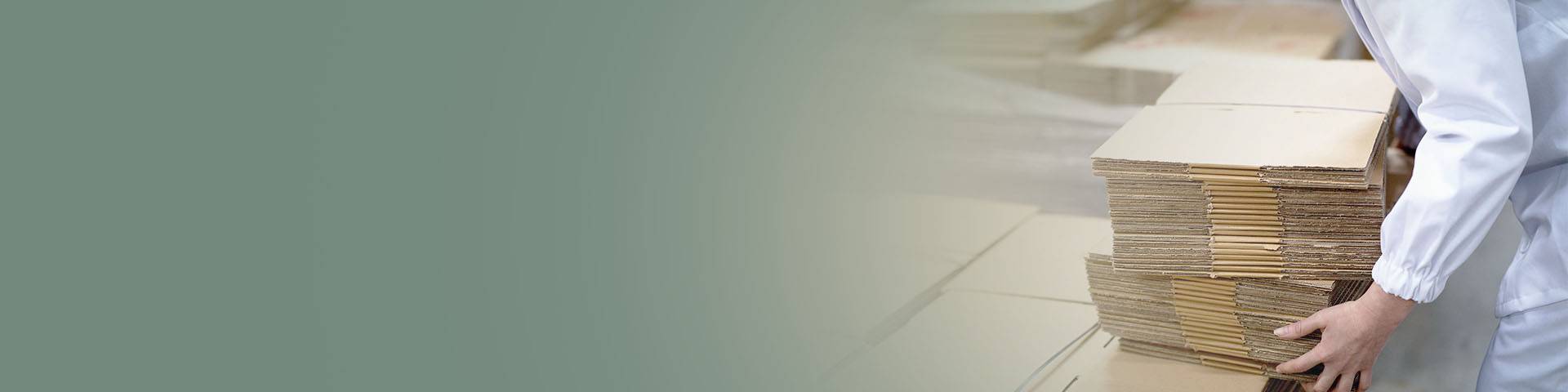 Worker in the packaging industry carrying a stack of cardboard