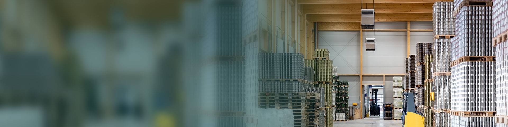 Logistics hall equipped with industrial air purifiers with stacked cans on pallets.