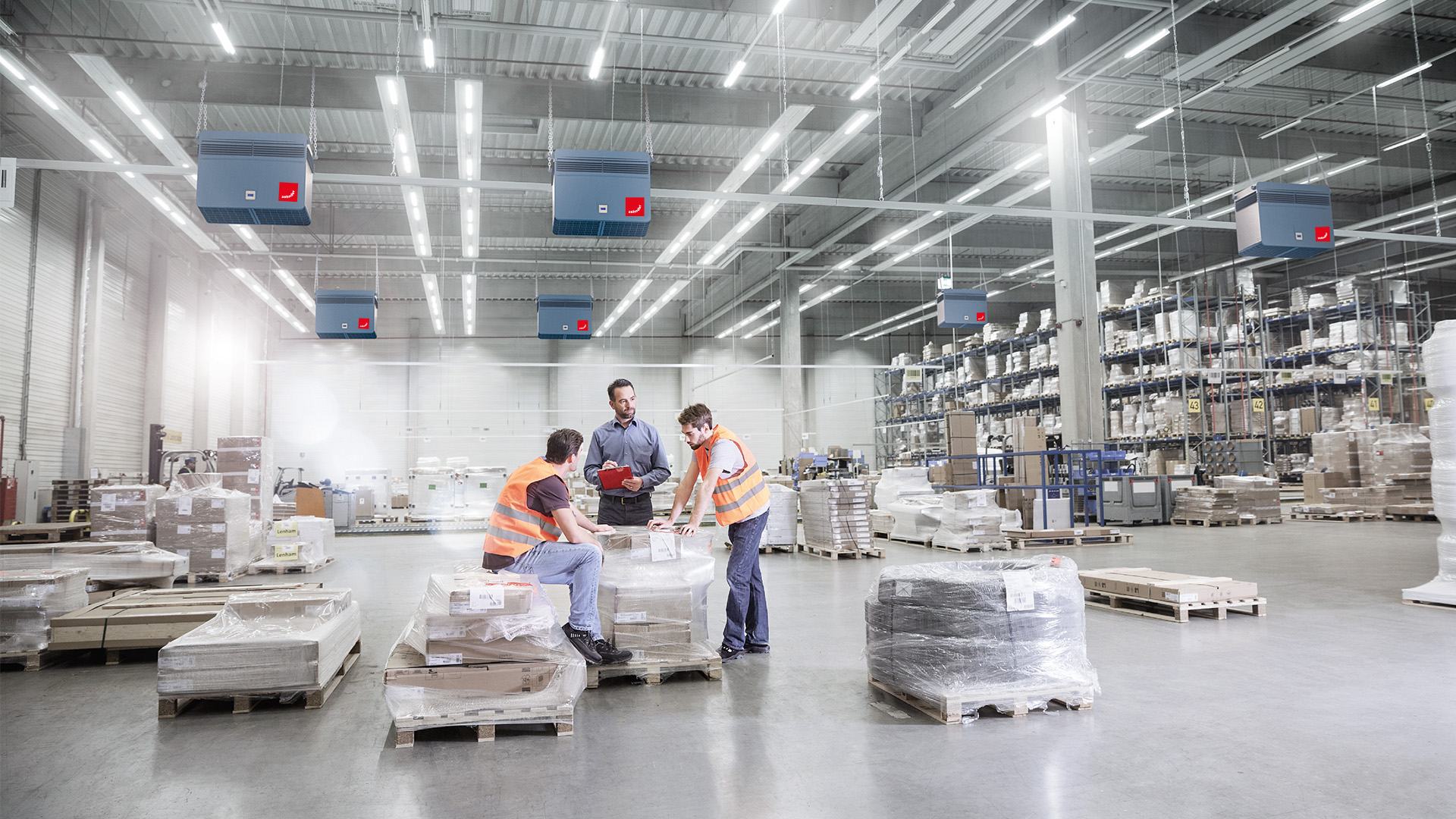 Employees confer in a warehouse equipped with industrial air purifiers from Zehnder Clean Air Solutions.