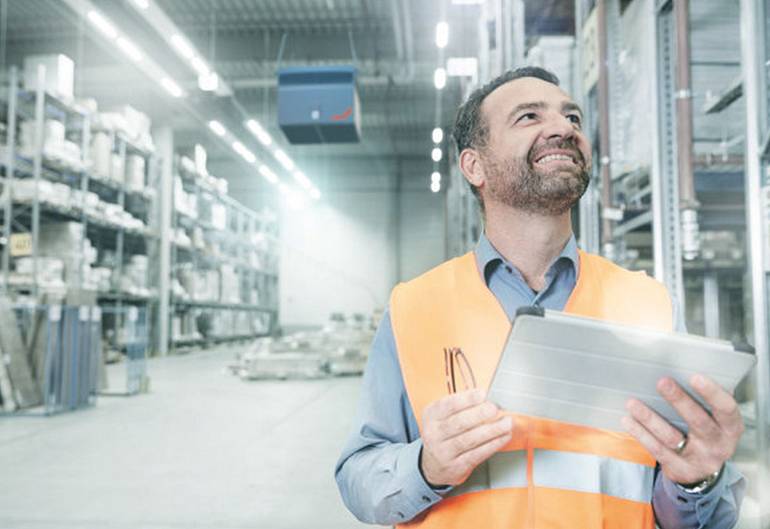 Smiling service manager in a clean warehouse with industrial air purification checking the air quality