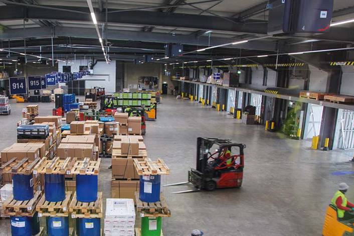Employee drives through a logistics hall with a forklift truck.