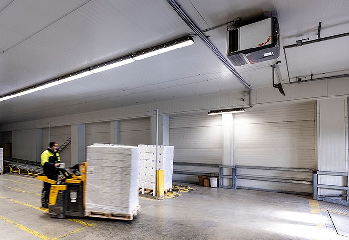Employee driving a forklift truck through a warehouse.