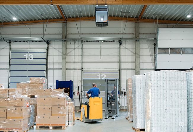 Luftreiniger in einer Halle, in der Kartons gestapelt sind.