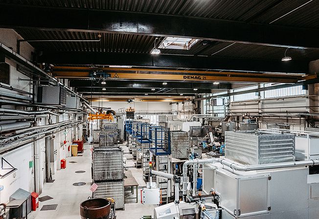 Industrial hall with machines, metal cages and crane system.